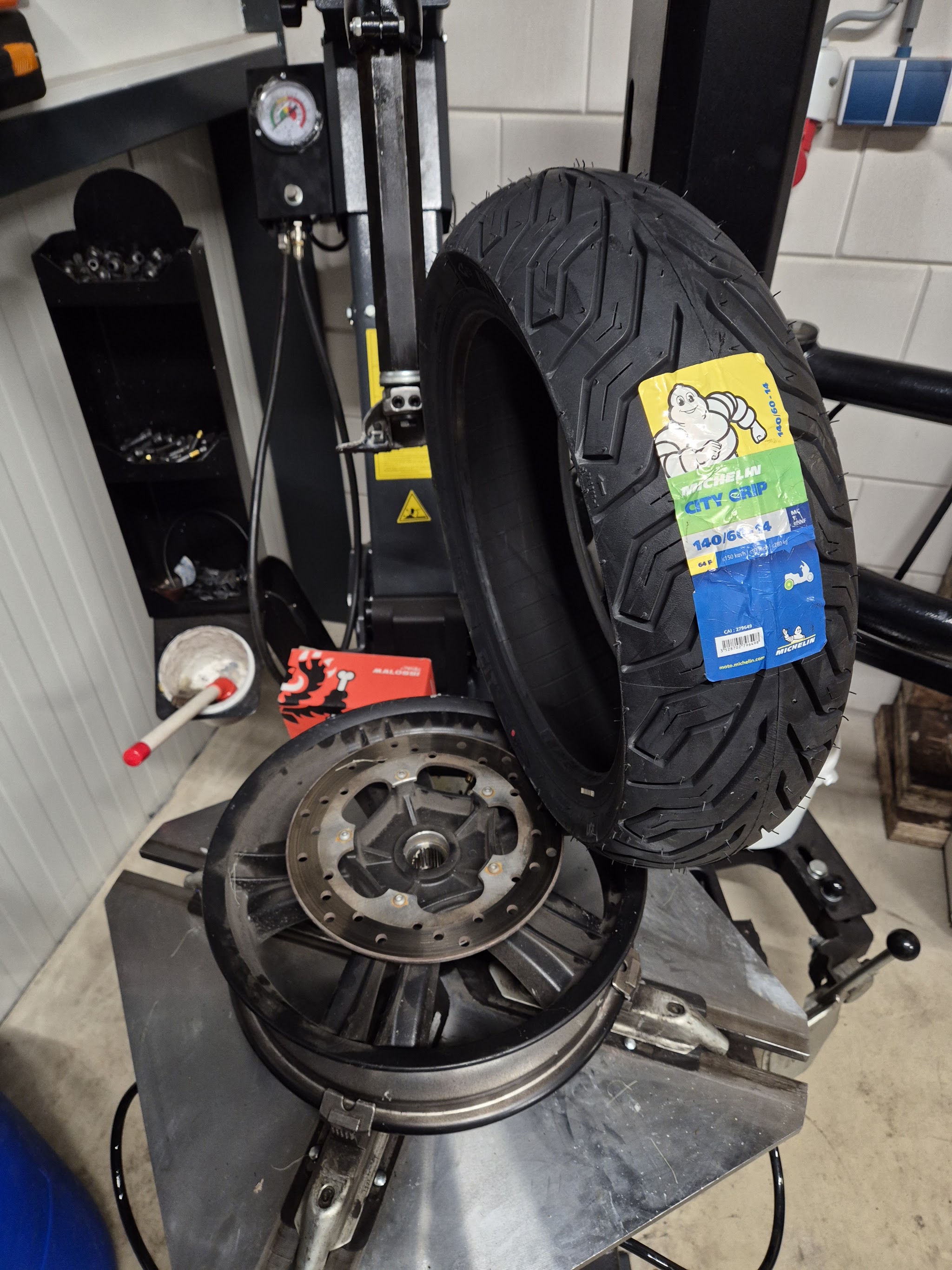 Nieuwe Michelin scooterband naast het wiel op de bandenwisselmachine